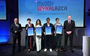 Na zdjęciu grupa osób stojących na scenie podczas ceremonii wręczenia nagród konkursu „Młody Wynalazca”. 